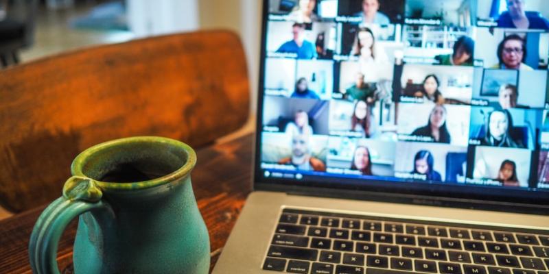 Online meeting: coffee mug by laptop with participants on screen