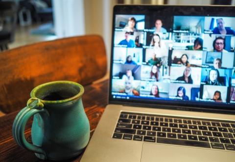 Online meeting: coffee mug by laptop with participants on screen